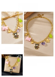 Detail of gold chain necklace featuring bear, flower, and heart charms in a cute style