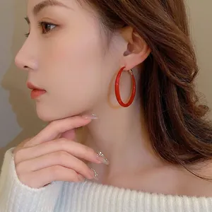 Minimalist Ancora red enamel hoop earrings with gold metal posts worn by model