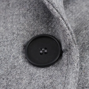 Detail of grey coarse wool fabric featuring a classic black four-hole button closure