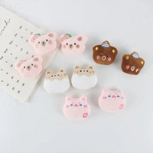 Close-up of cute plush bear and cat charms with detailed embroidery for DIY fashion