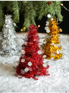 Mini Christmas cone trees with colorful sequins on white snow background with warm lights