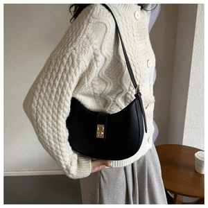 Detail of a black hobo shoulder bag with a gold metal clasp and matte leather texture