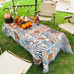 Bohemian knit picnic blanket with sun patterns and fringe on outdoor lawn