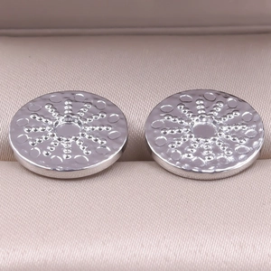 Macro shot of silver stainless steel round earring studs with textured design details
