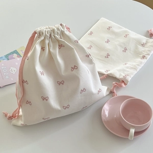 Detailed view of cream cotton drawstring bags with pink bow prints and ribbons