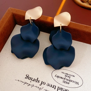 Macro detail of irregular navy blue matte petal earrings with gold metal accents