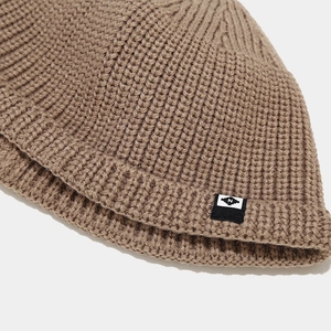 Détail du tricot à grosses côtes et de l'étiquette logo N sur un bonnet marron