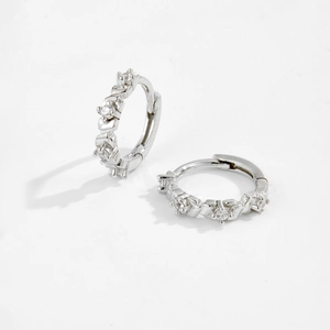 Macro shot of 925 sterling silver hoop earrings with clear inlaid stones on white base