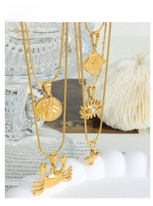Close-up of gold titanium steel layered necklaces with bee and coin animal pendants