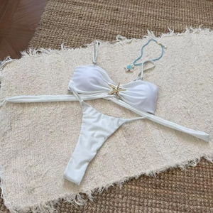 Flat lay of white two-piece bikini featuring a decorative gold starfish metal accessory