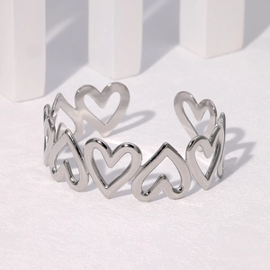 Detailed close-up of a silver hollow heart-shaped adjustable cuff bracelet on a pedestal
