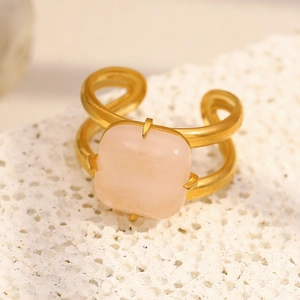 Détail de la bague plaquée or 18 carats avec pierre carrée rose sur surface minérale