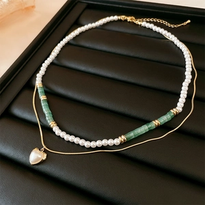 Elegante collana a due strati di perle barocche con dettagli verdi e pendente a cuore