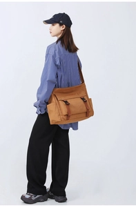 Sac bandoulière en toile marron avec boucles porté par un mannequin en studio photo