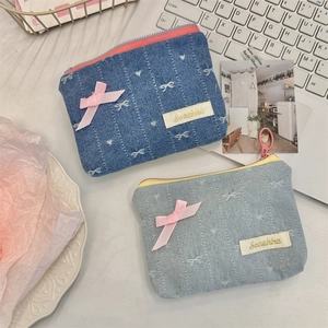 Detail of denim coin purses with embroidered bows, pink ribbons and secure zipper