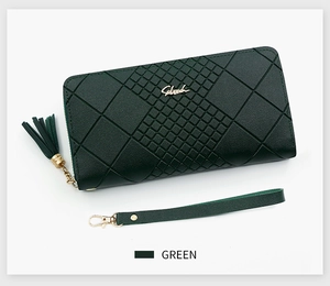 Detail of dark green quilted long wallet featuring gold zipper, tassel and wristlet strap