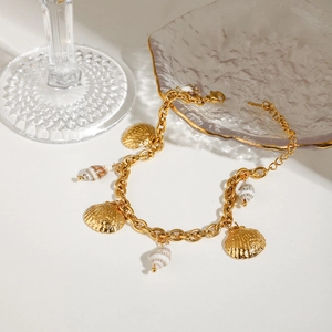 Detailed view of a gold shell charm bracelet featuring conch and scallop pendants