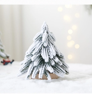 Close-up of mini flocked Christmas tree with snow effect on a wooden base with bokeh lights