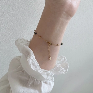 Dettaglio del bracciale con perline blu stellato e ciondolo inciso sul polso