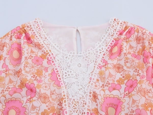 Dettaglio dello scollo a V con pizzo bianco e tessuto in chiffon a fiori rosa