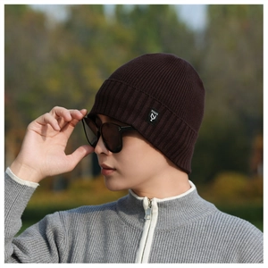 Close-up of deep brown ribbed knit beanie with a brand tag in a scenic outdoor setting