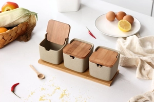 Close-up of Japanese ceramic seasoning jars with wooden lids and spoons on a wood tray