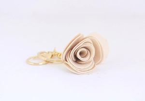 Détail d'un porte-clés rose en tissu beige avec un anneau en métal doré élégant