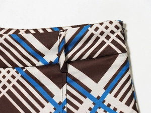 Détail du pantalon à carreaux marron et bleu avec fermeture éclair latérale et passants