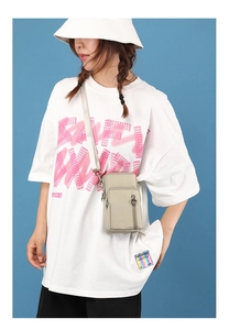 Detail of cream mini crossbody phone bag with metal heart zipper on navy background