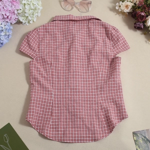 Detailed view of red plaid short sleeve shirt with classic collar and fabric buttons