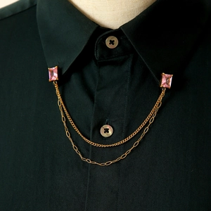 Dettaglio di spille da colletto con cristallo rosa e catene d'oro su camicia nera elegante