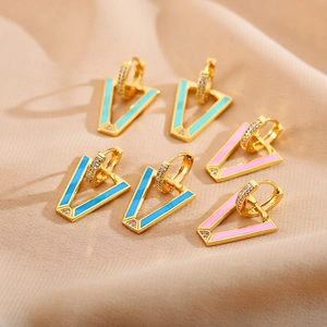 Three pairs of V-shaped gold earrings with mint green, blue, and pink enamel on beige fabric