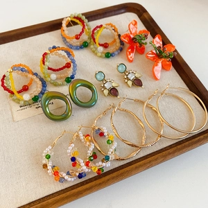 Collection of vintage glass flower earrings and beaded hoops on a wooden jewelry tray