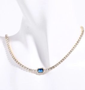 Detail of 18K gold-plated tennis necklace with emerald-cut blue crystal on a white bust