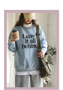 Detail of light blue crewneck sweatshirt with Leave it all behind text print