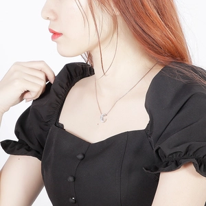 Elegant silver-tone crescent pendant necklace worn on neck with black puff sleeve dress