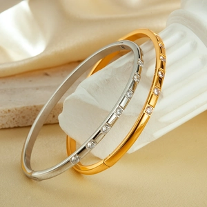 Detail of gold and silver stainless steel bangles with square-set cubic zirconia stones