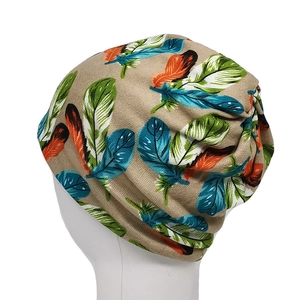 Detailed view of elastic knit beanie featuring colorful feather patterns on tan fabric