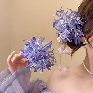 Détail de la pince à cheveux fleur en tissu violet avec pompon long et pétales floraux