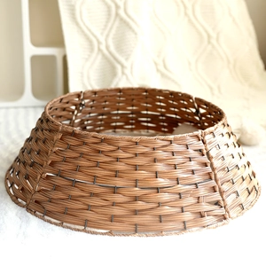 Brown woven Christmas tree collar with metal frame on white rug for festive home decor