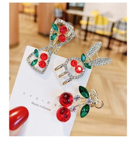 Detailed view of mini cherry hair claw clips set with sparkling red and green rhinestones