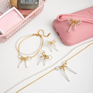 Elegant gold bow jewelry set with white pearls including necklace, bracelet and ring