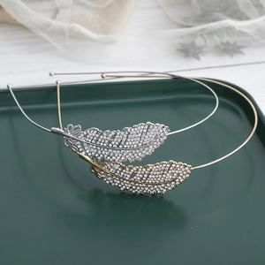 Elegant gold and silver metal feather headbands with sparkling rhinestones set on a tray
