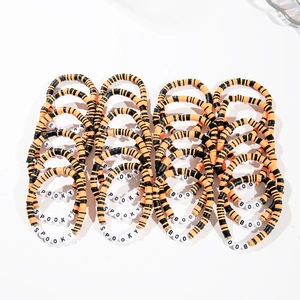 Detail of Halloween beaded bracelets with orange and black Heishi beads and Spooky lettering