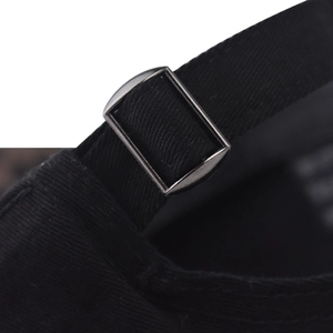 Détail de la boucle métallique et de la sangle en sergé noir de la casquette