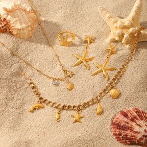 Golden sea star and shell jewelry set with starfish pendants on a sandy beach