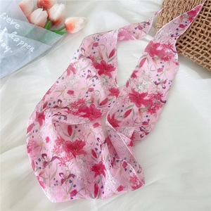 Close-up of floral silk scarf with pink lily patterns and delicate stitched edges