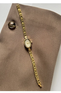 Vue détaillée du cadran ovale doré avec chiffres romains sur une montre rétro chic
