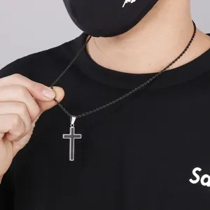 Close-up of hip hop style black cross pendant with silver edges on a woven chain necklace