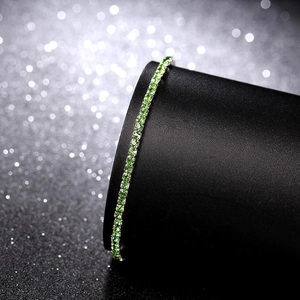 Macro shot of 2.0mm silver bracelet with green crystals on black cylindrical stand